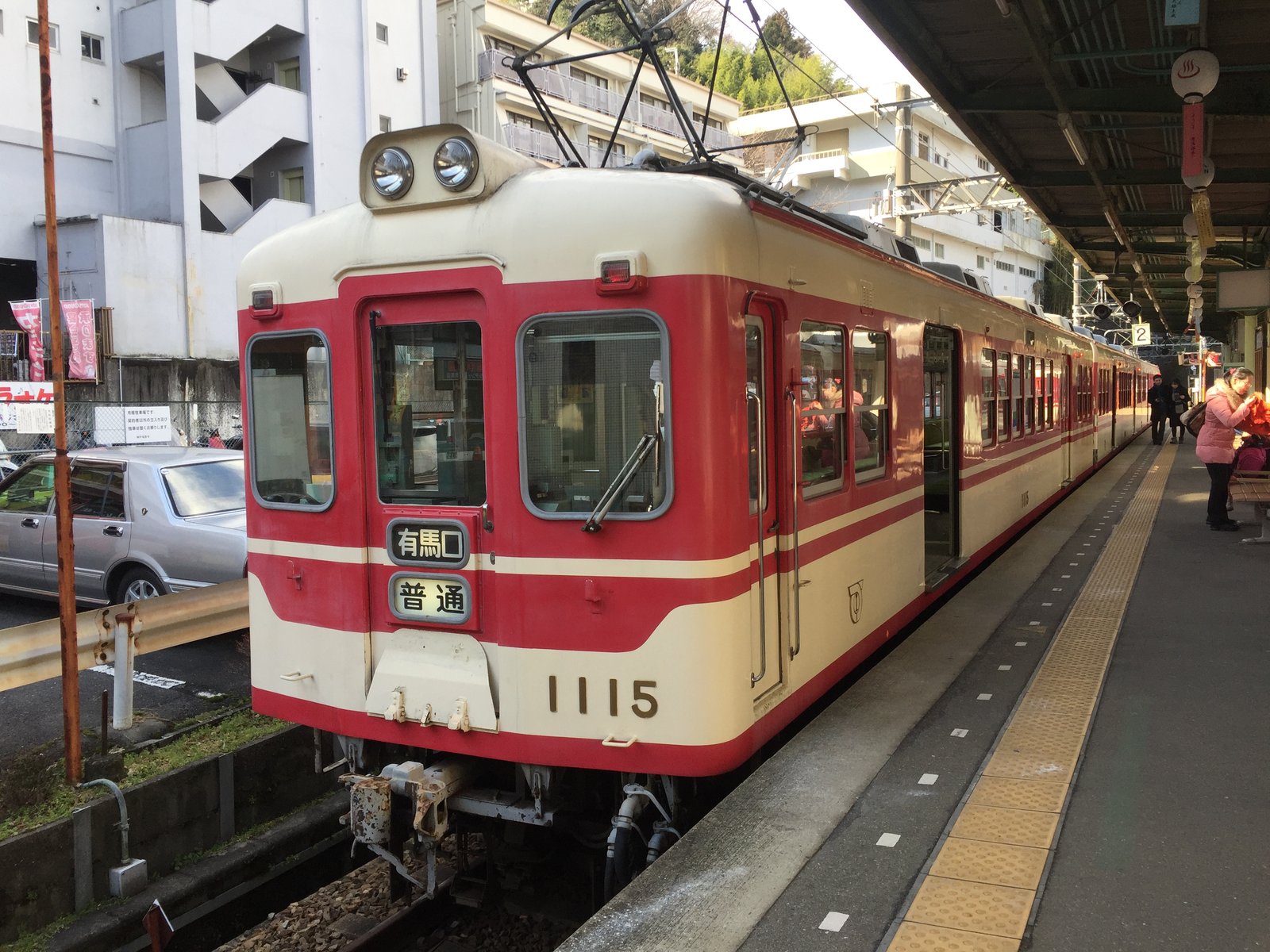 有馬温泉駅のホームに停まる、赤とクリーム色の神戸電鉄1100系。前面の行先表示は「有馬口 普通」