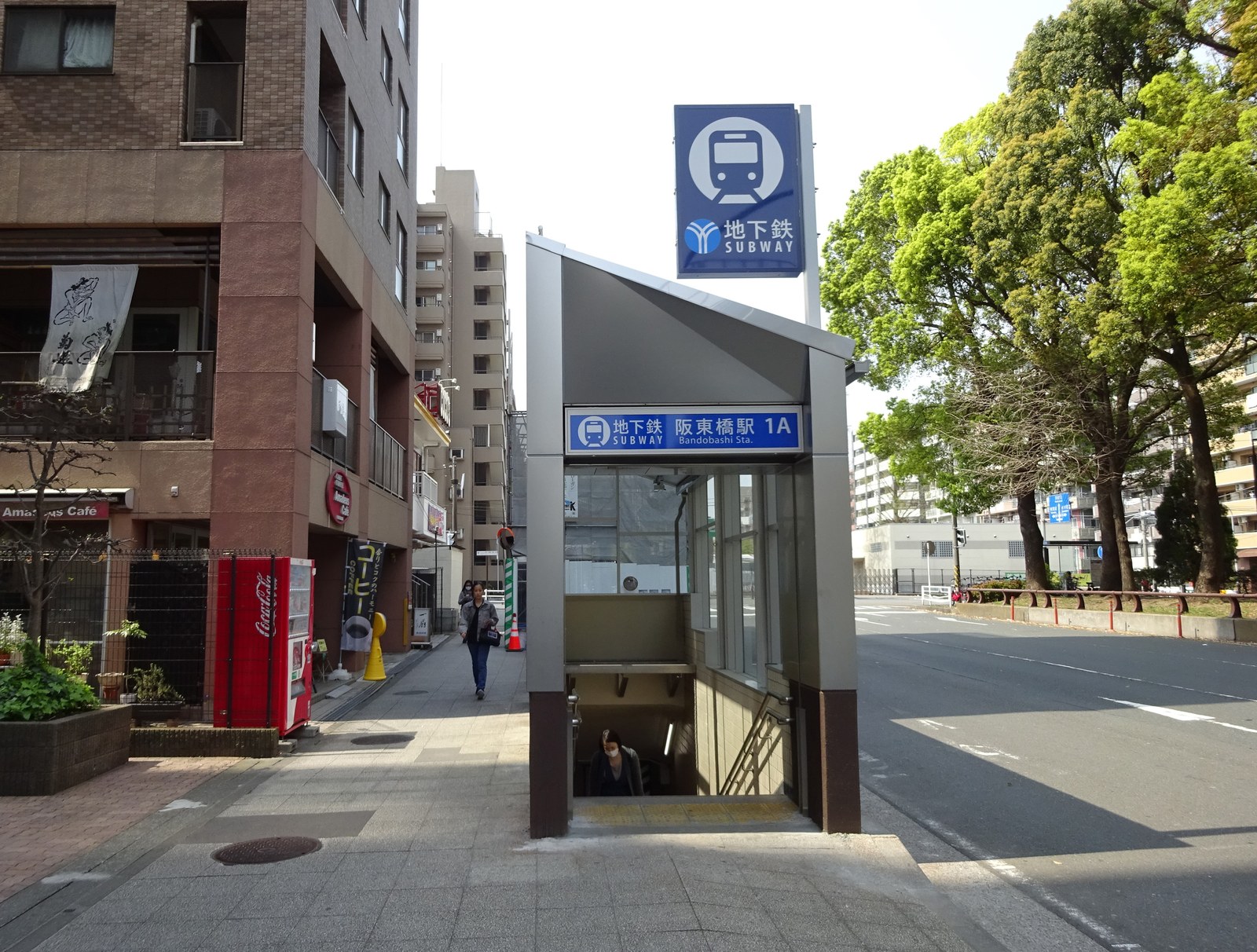 横浜市営地下鉄の阪東橋駅の出口 1A。歩道に地下へ下りる階段の上屋があり、青い地下鉄の看板が立っている