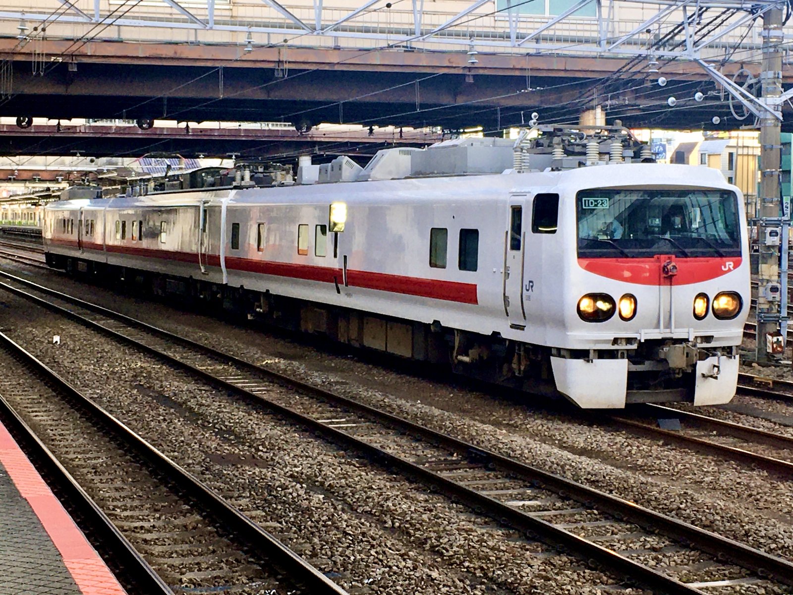駅の構内を走る白い車体に赤い帯の3両編成の電車。先頭に「ID-23」の表示、屋根に測定用の機器