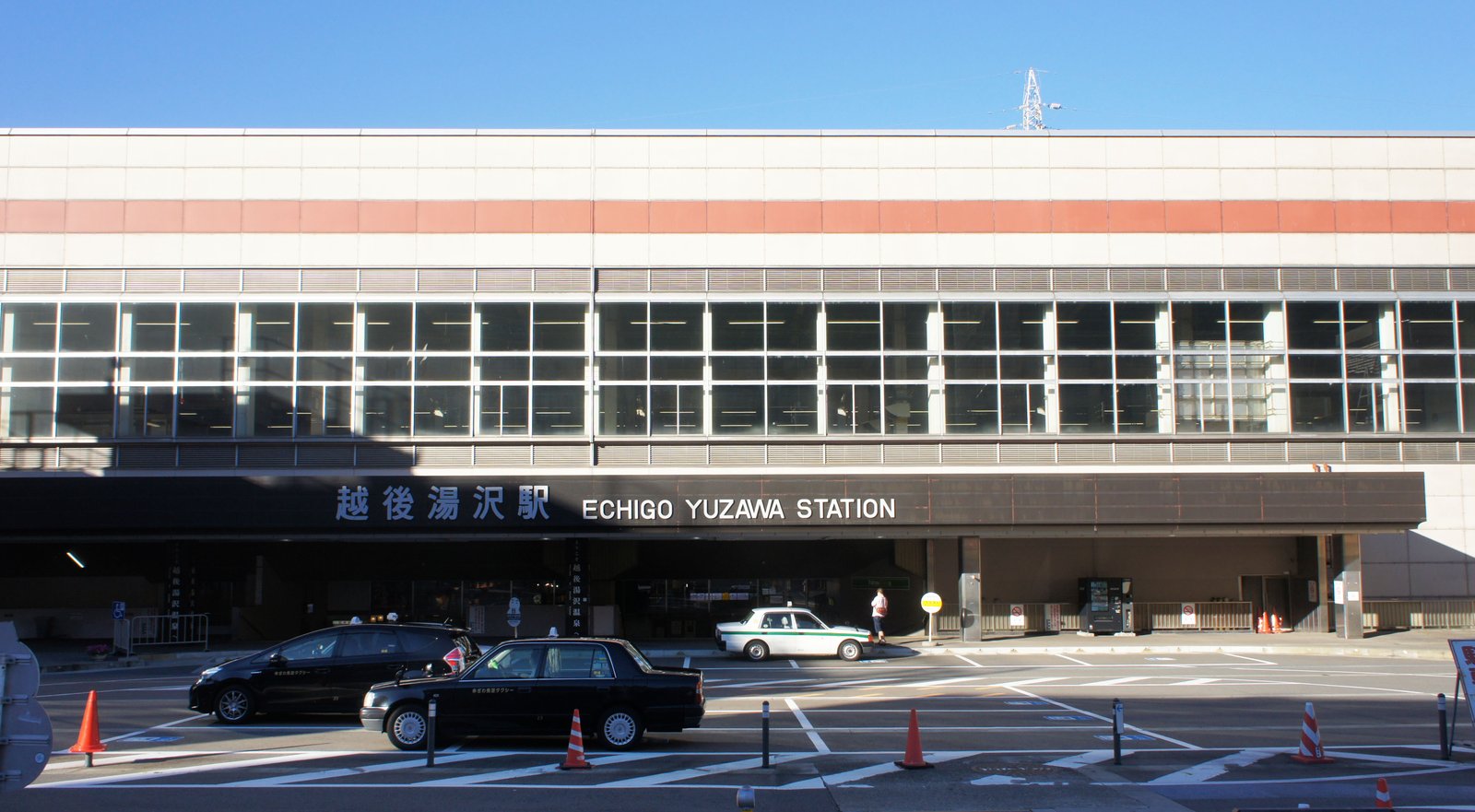 越後湯沢駅の西口駅舎。「越後湯沢駅 ECHIGO YUZAWA STATION」の看板の下に、タクシーが3台並んでいる