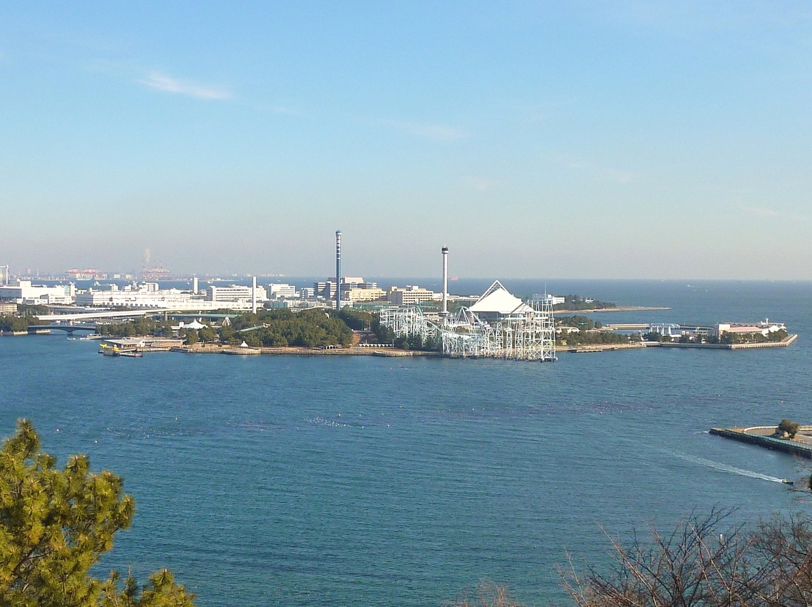 野島公園の高台から見た横浜・八景島シーパラダイス。白い三角屋根の建物とアトラクションの塔が海に浮かぶ島に並ぶ