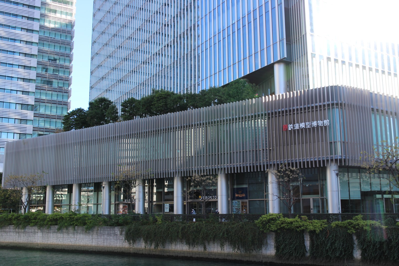 川沿いに建つ横浜三井ビルディングの低層部。縦の格子で覆われた2階の壁に「原鉄道模型博物館」の文字