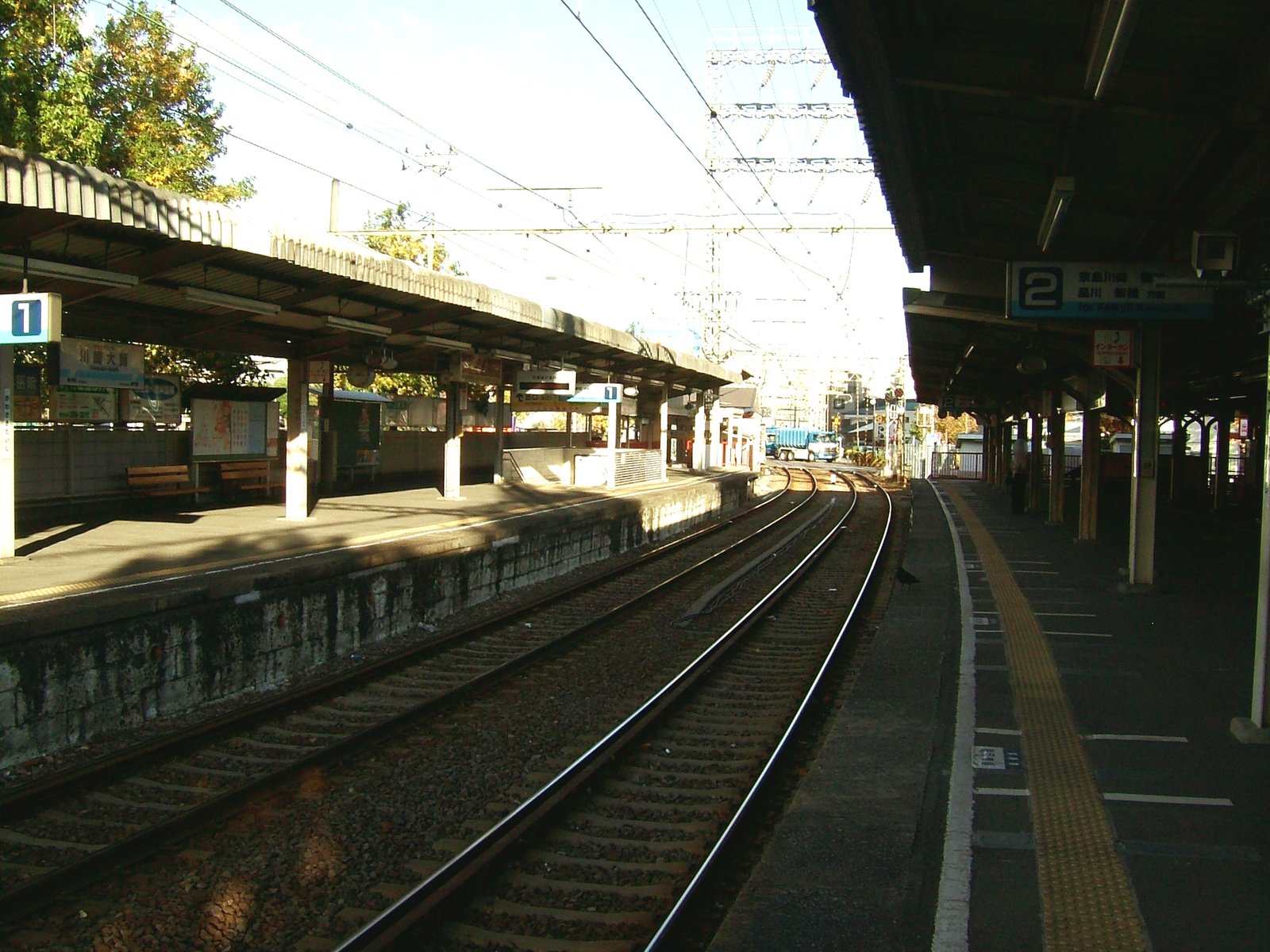 京急大師線の川崎大師駅のホーム。屋根のある2本のホームの間を線路が右へ緩く曲がり、2番線の案内板に京急川崎・品川方面と書かれている