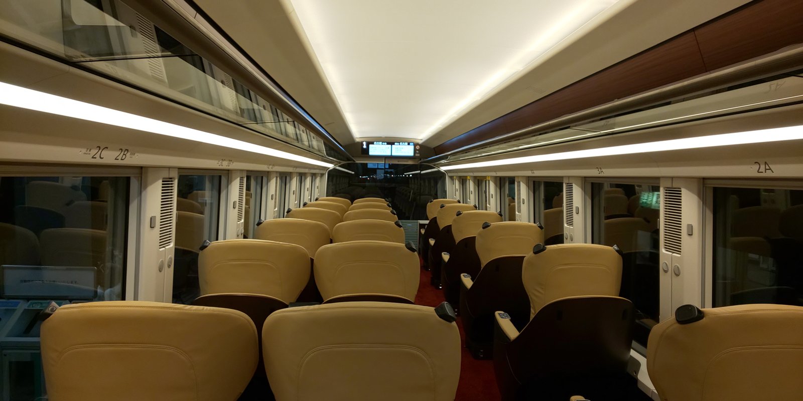 ひのとりのプレミアム車両の車内。ベージュの本革の座席が通路をはさんで1列と2列の3列に並び、床は赤いカーペット