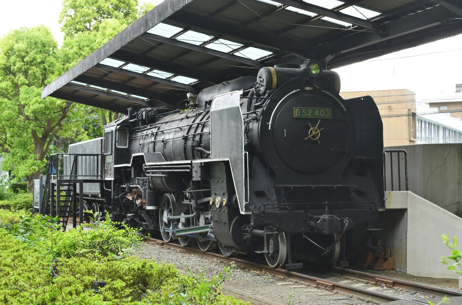 屋根の下に保存された黒い蒸気機関車。前面に「D52 403」のナンバープレート、脇に見学用の階段と台がある