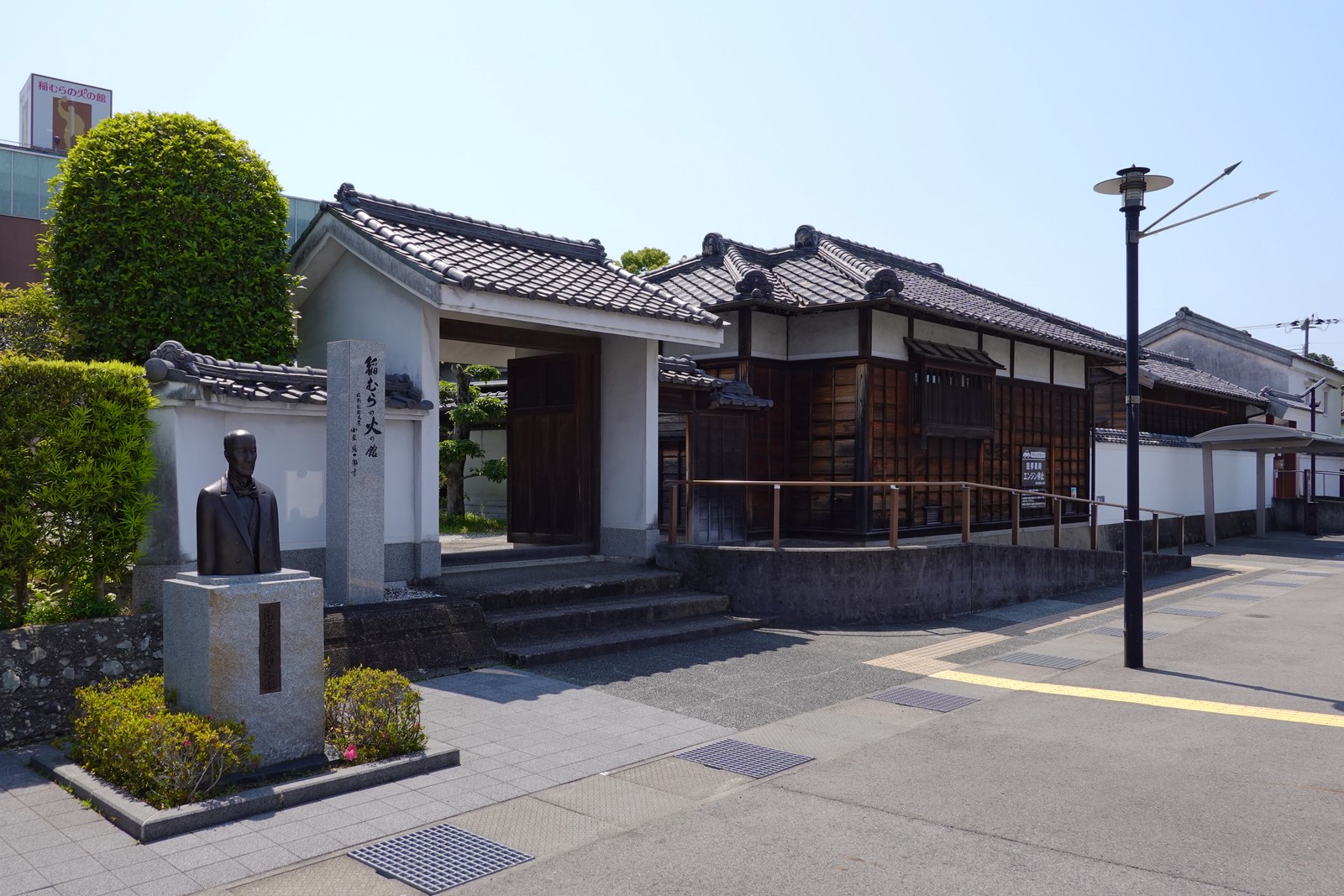 濱口梧陵記念館の正門。瓦屋根の門の手前左に濱口梧陵の胸像と「稲むらの火の舘」の石碑が立ち、白壁越しに記念館の瓦屋根が見える