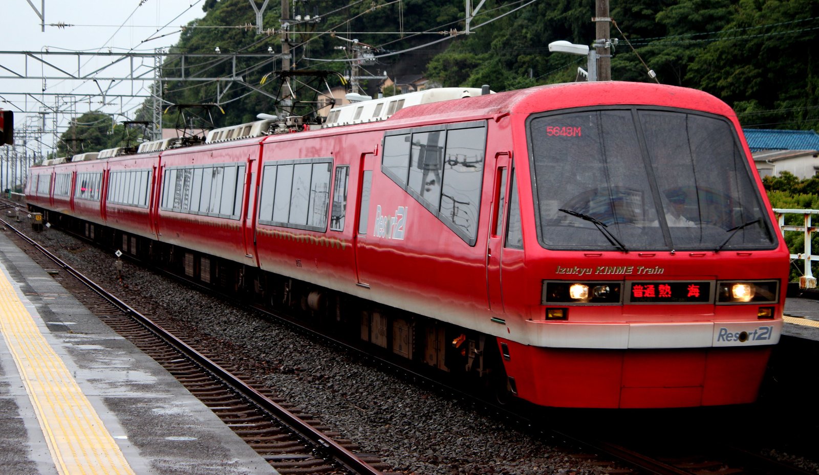 赤い車体に白い帯の伊豆急行リゾート21が駅に入ってくる。前面に「Izukyu KINME Train」の文字と「普通 熱海」の表示