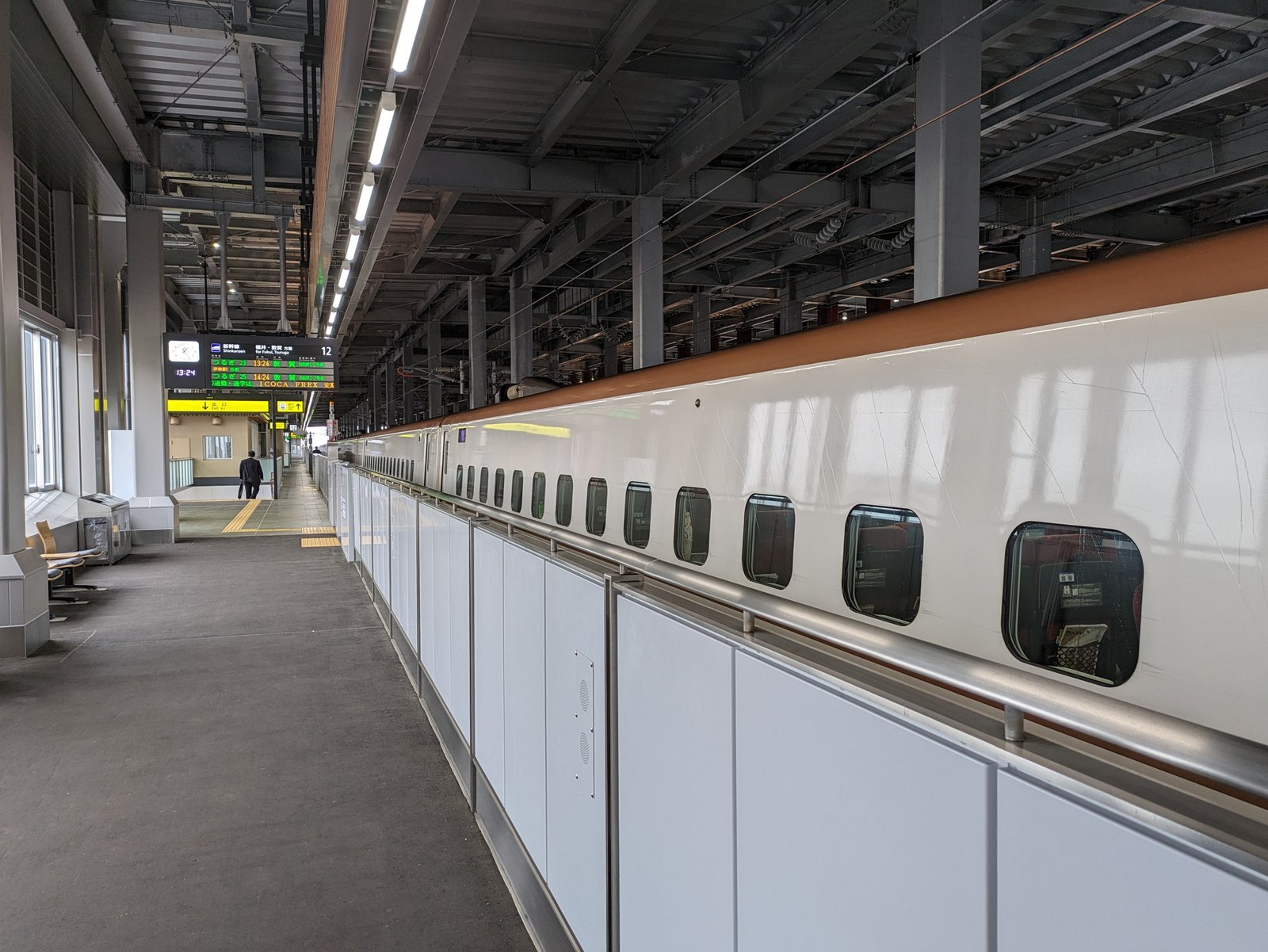 北陸新幹線の加賀温泉駅ホームに停まる白い車体の新幹線と、発車案内の電光掲示板。つるぎ23号・25号の福井・敦賀方面の表示が見える
