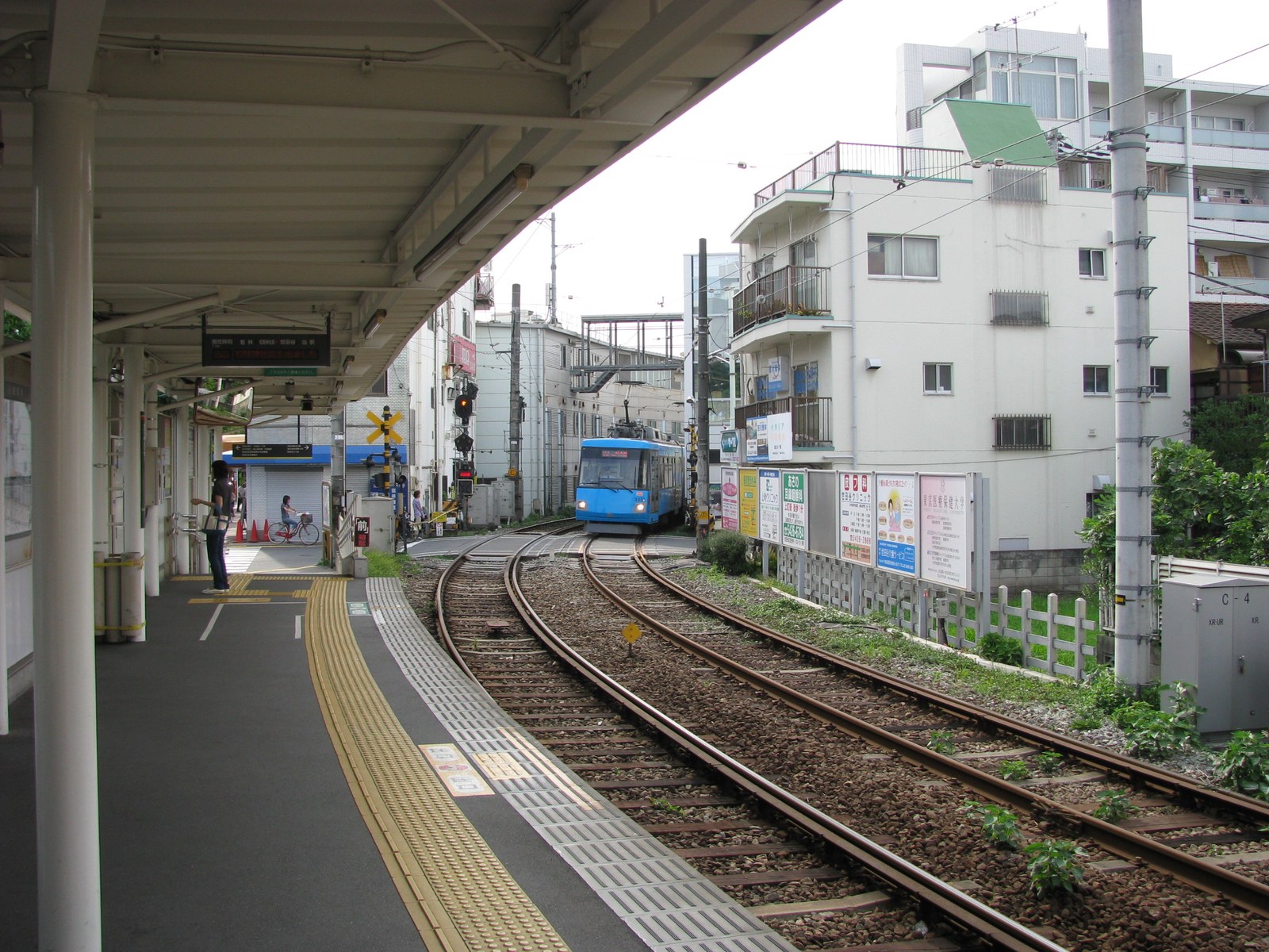 東急世田谷線の上町駅のホーム。カーブした線路の先に青い電車が見える