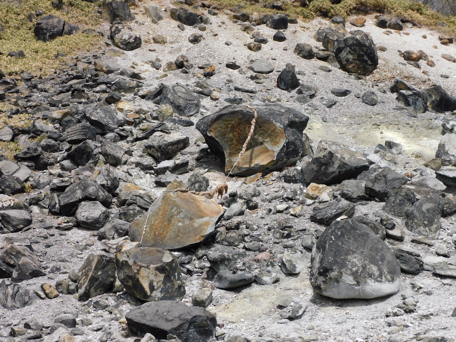 硫黄で変色した那須岳山麓の岩場に、しめ縄を巻かれた殺生石が三つに割れて横たわっている