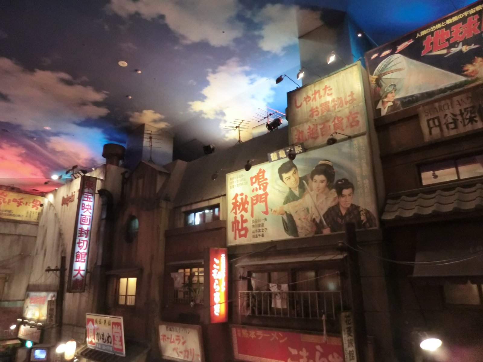 館内に再現された昭和の街並み。夕焼け色の天井の下にレトロな映画看板の建物が並ぶ