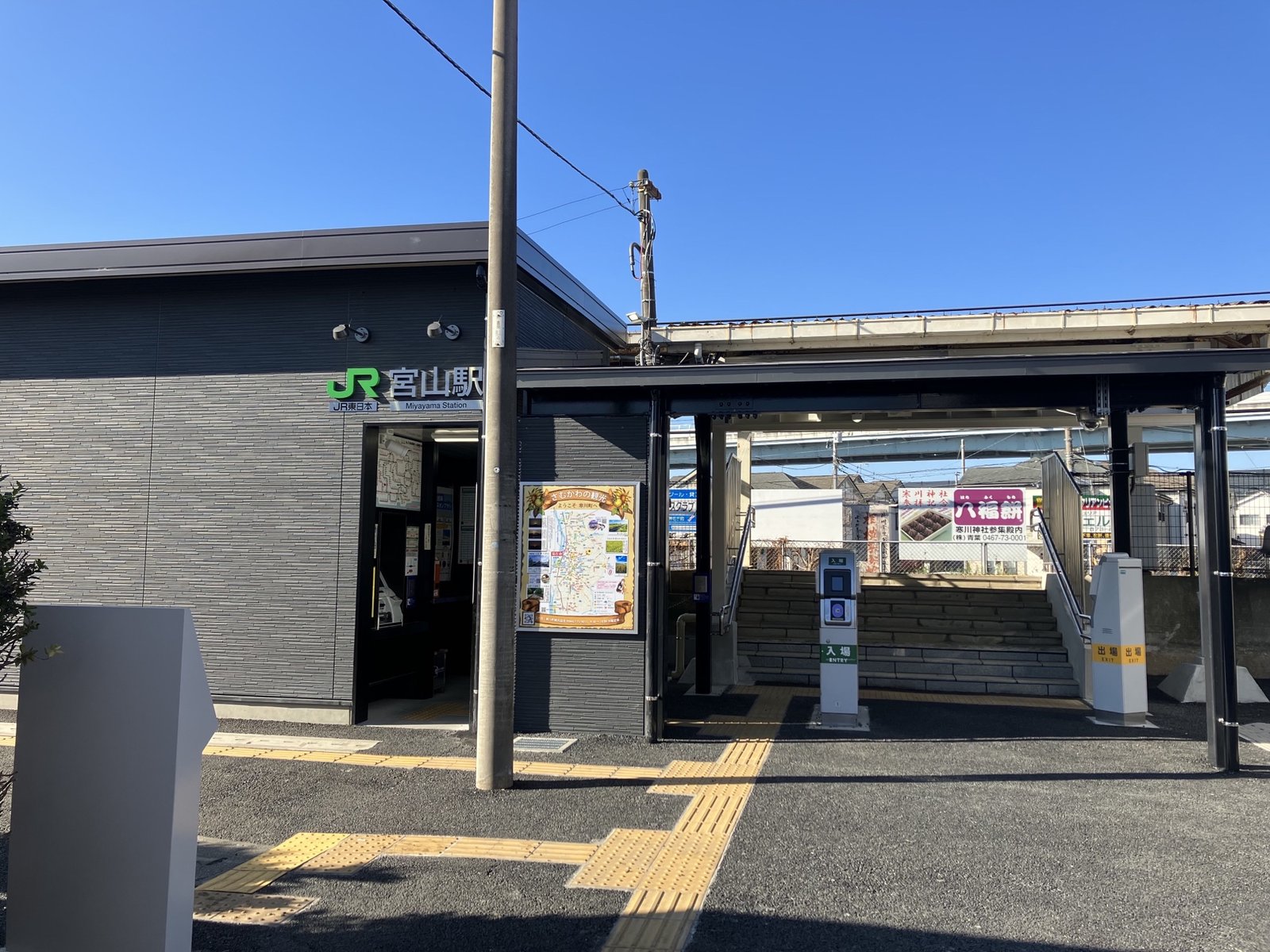 JR相模線の宮山駅。黒い壁の平屋の駅舎に「JR 宮山駅」の看板が付き、右にホームへ上がる階段と改札機が見える