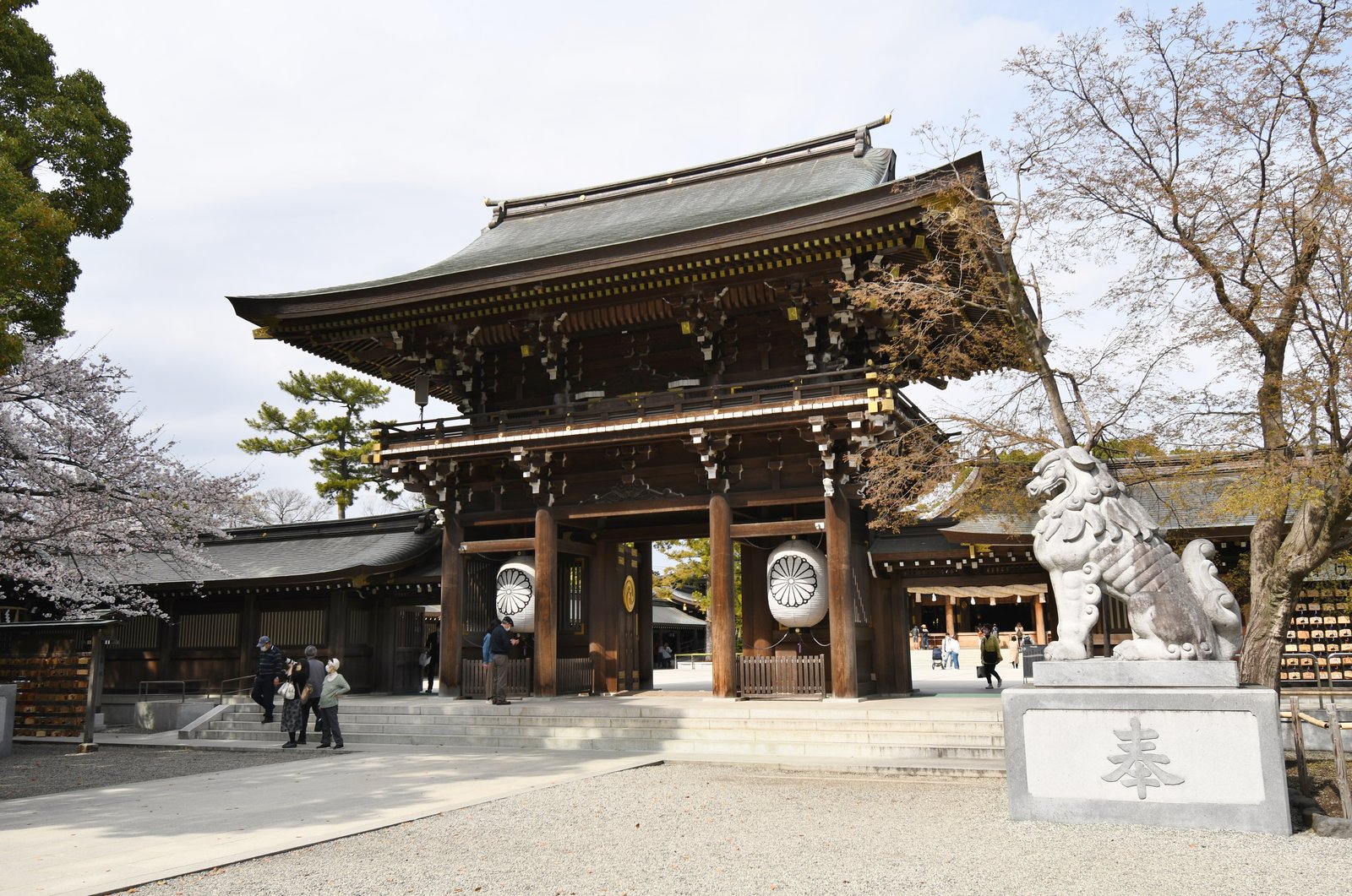寒川神社の神門。石段の上に建つ二階建ての木造の門で、両脇の柱に大きな白い提灯が下がり、右手前に石の狛犬が座る