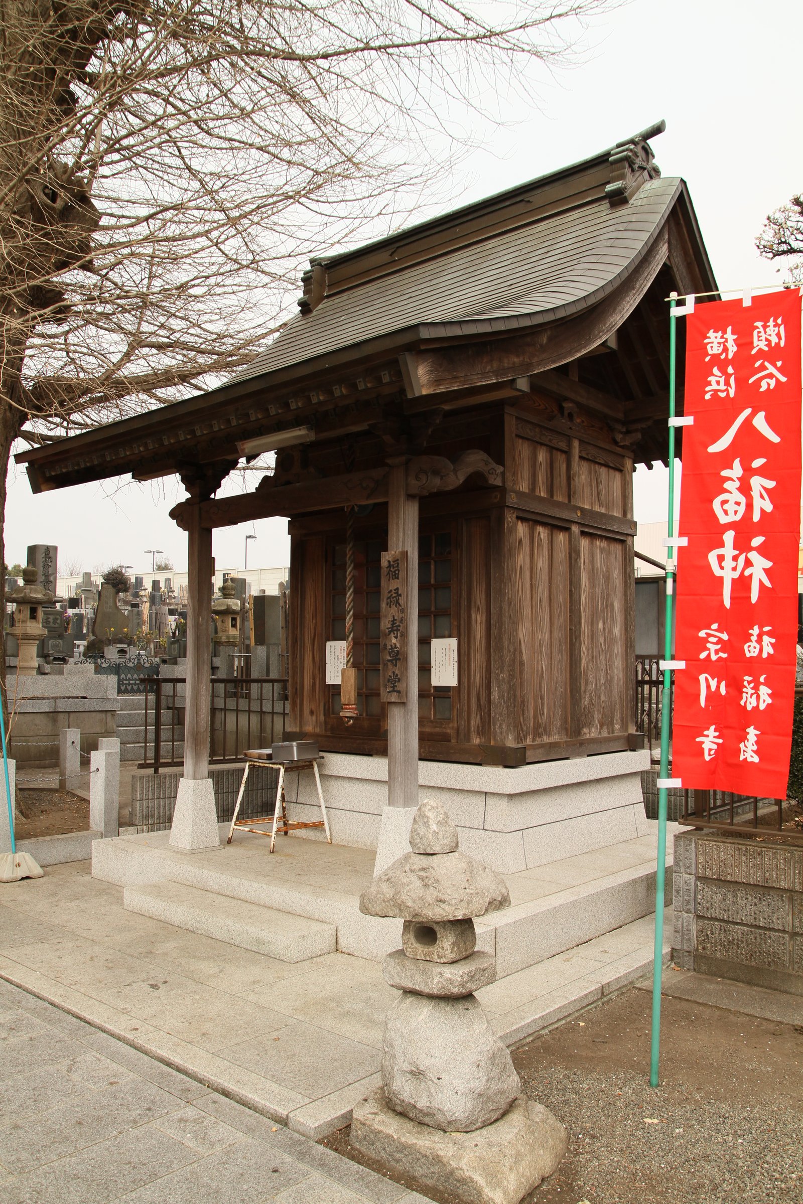 宗川寺の福禄寿尊堂。瓦屋根の木造の小さな堂で、柱に「福禄寿尊堂」の札が掛かり、右に「八福神」の赤いのぼり、左奥に墓地が見える