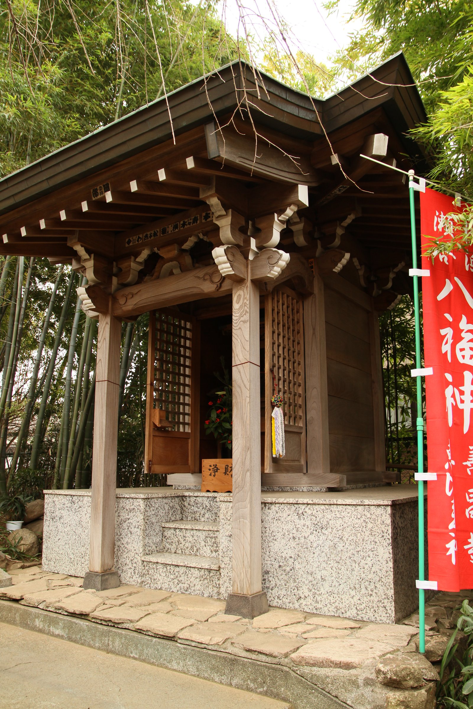 善昌寺の恵比寿堂。白壁に木の格子戸の小さな堂で、両脇に橙色の灯籠が立ち、右に「八福神」の赤いのぼり