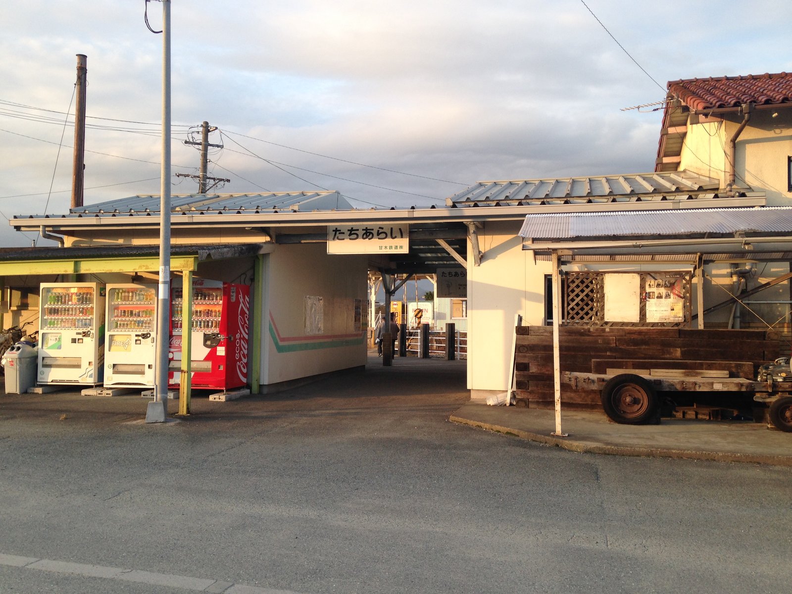 白い壁と金属の屋根をもつ平屋の駅舎。中央の通路の上に「たちあらい 甘木鉄道」の駅名板が掛かり、左に自動販売機が並ぶ