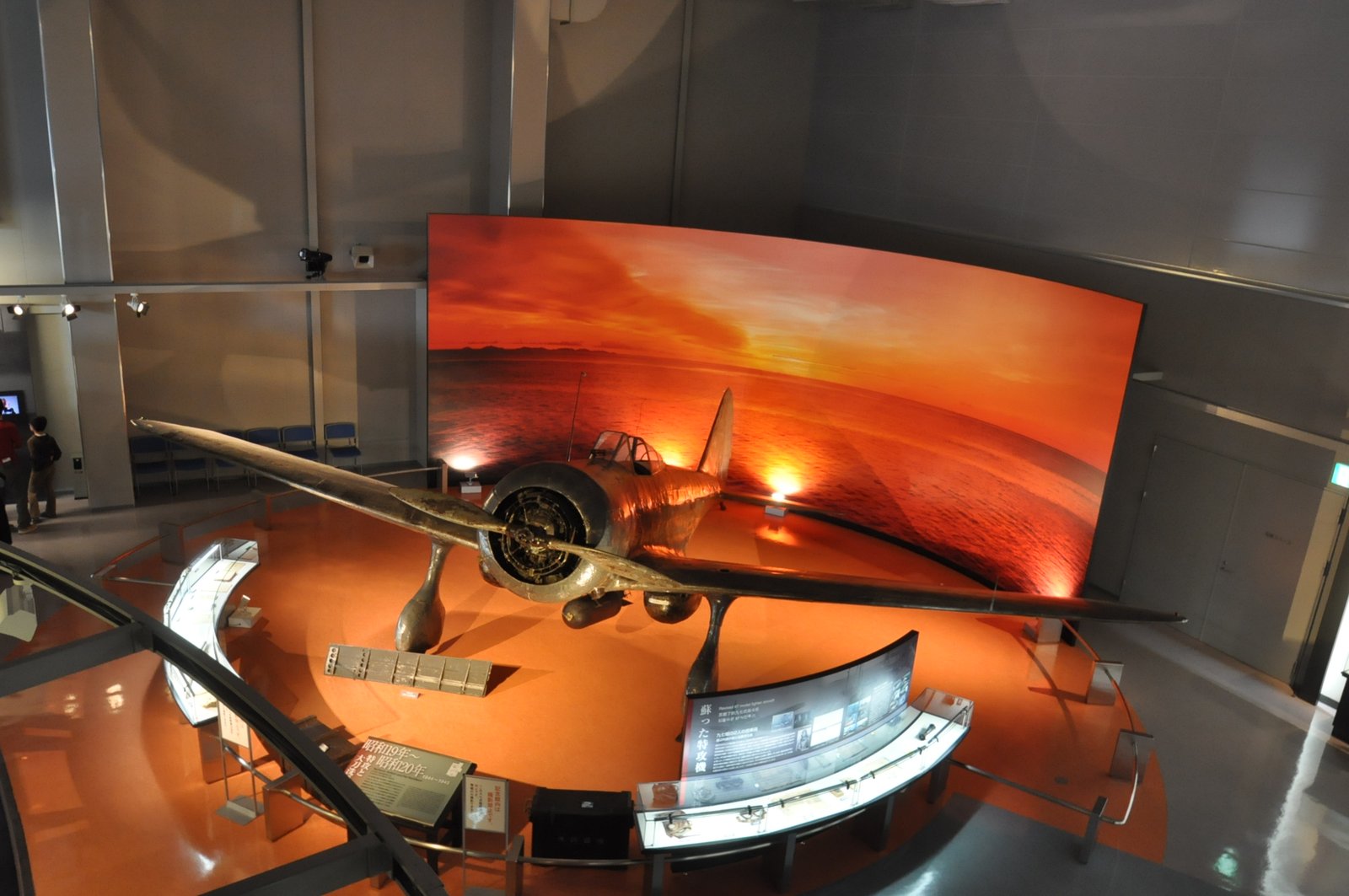 展示室に置かれた九七式戦闘機。固定脚と細い胴体をもつ小型の単葉機で、金属の地肌が見える機体が床に据えられている