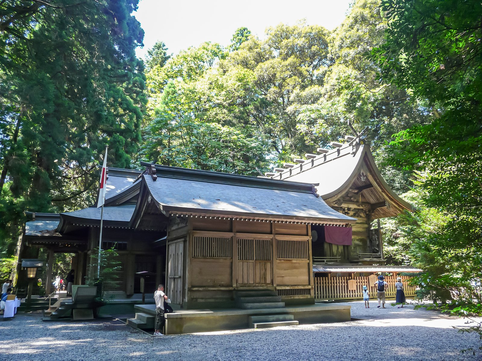 高千穂神社の拝殿(左)と本殿(右)。杉やクスの木立を背に、玉砂利の境内に木造の社殿が並んでいる