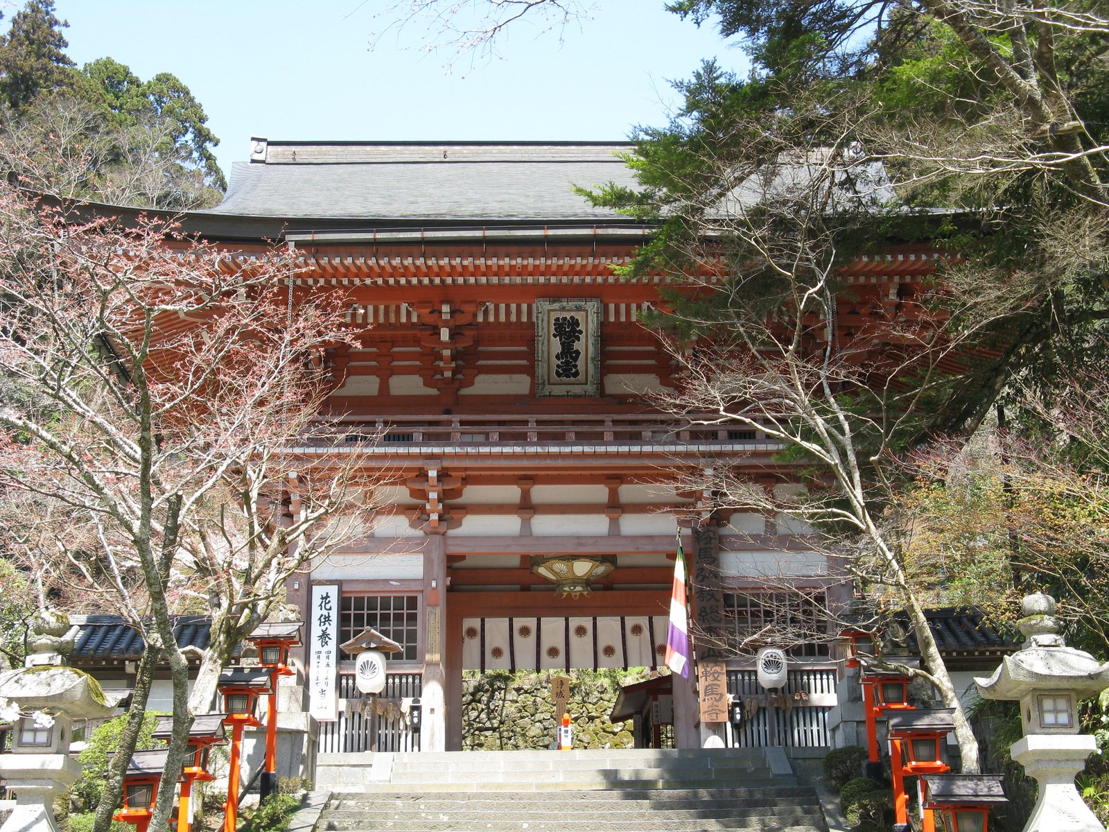 鞍馬寺の山門。朱塗りの二階建ての門で、中央に「鞍馬寺」の扁額が掛かり、石段の両脇に朱の灯籠が並ぶ