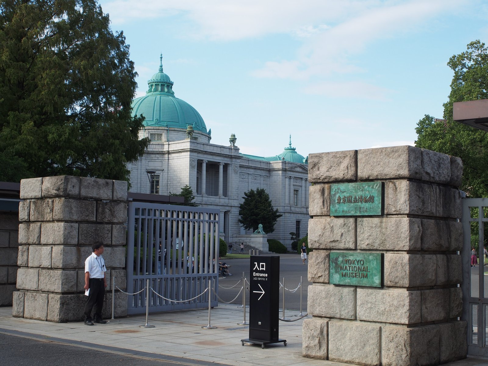 石積みの門柱に「東京国立博物館」と「TOKYO NATIONAL MUSEUM」の銘板が付いた正門。門の奥に緑青のドームを載せた白い石造りの表慶館が見え、手前に「入口」の案内板が立つ