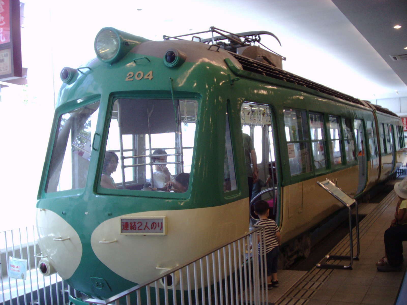 車内に子どもや大人が座るたま電デハ200形204号車の正面、緑とクリーム色の車体