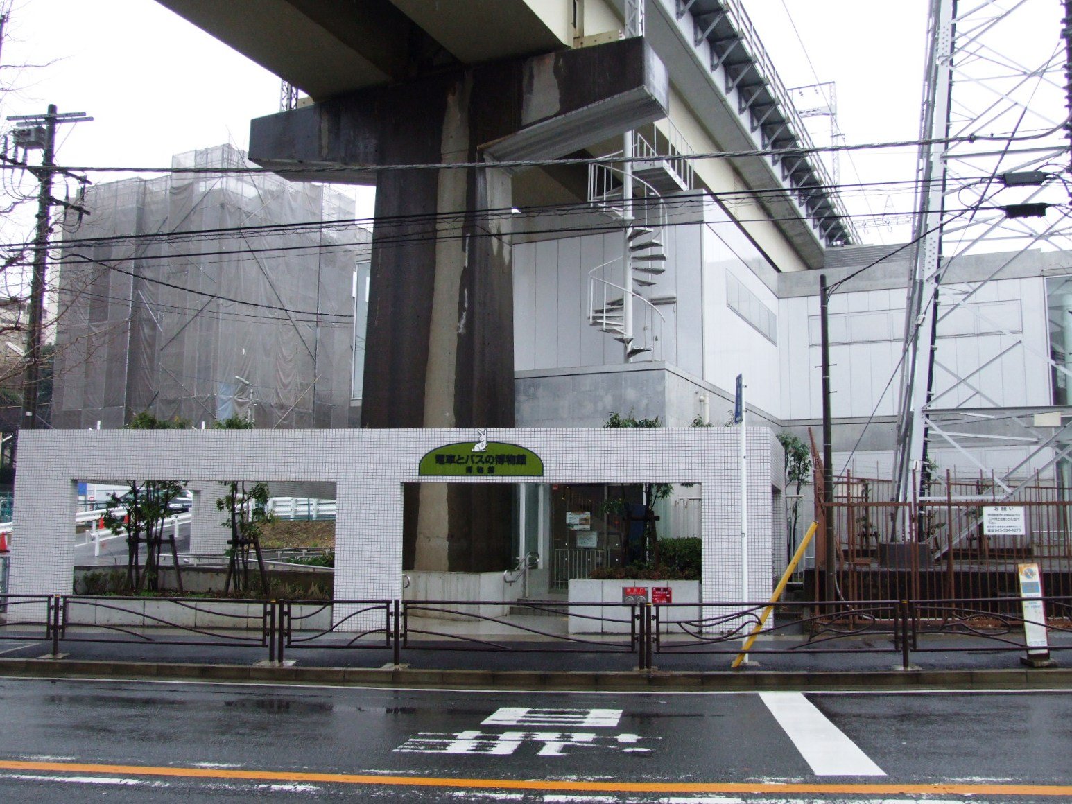 高架下の壁面に緑色の「電車とバスの博物館」の看板が掲げられた建物の外観