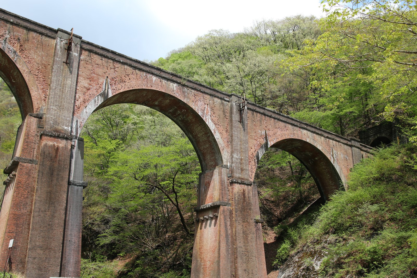 4連アーチのレンガ造りの橋、碓氷第三橋梁(めがね橋)。緑の木々の中にそびえる