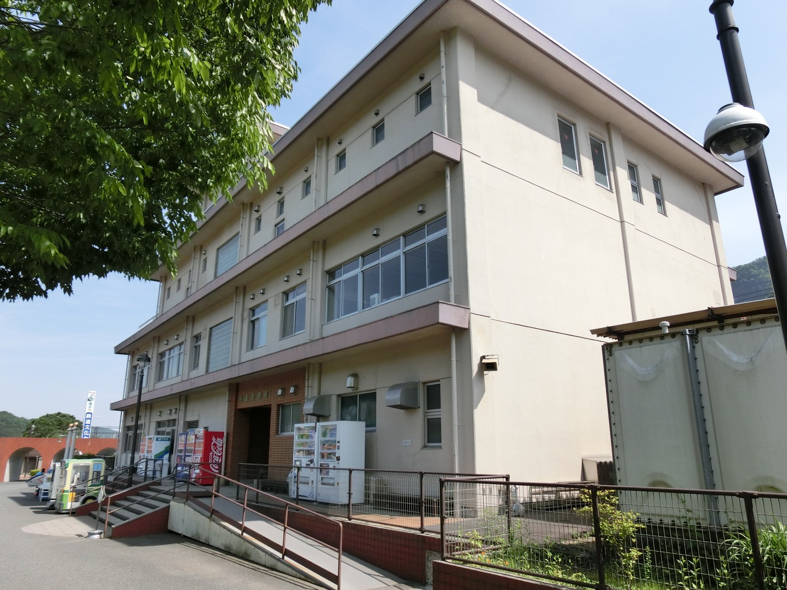 碓氷峠鉄道文化むらの鉄道資料館の建物。クリーム色の3階建てで、入口前に自動販売機とスロープがある