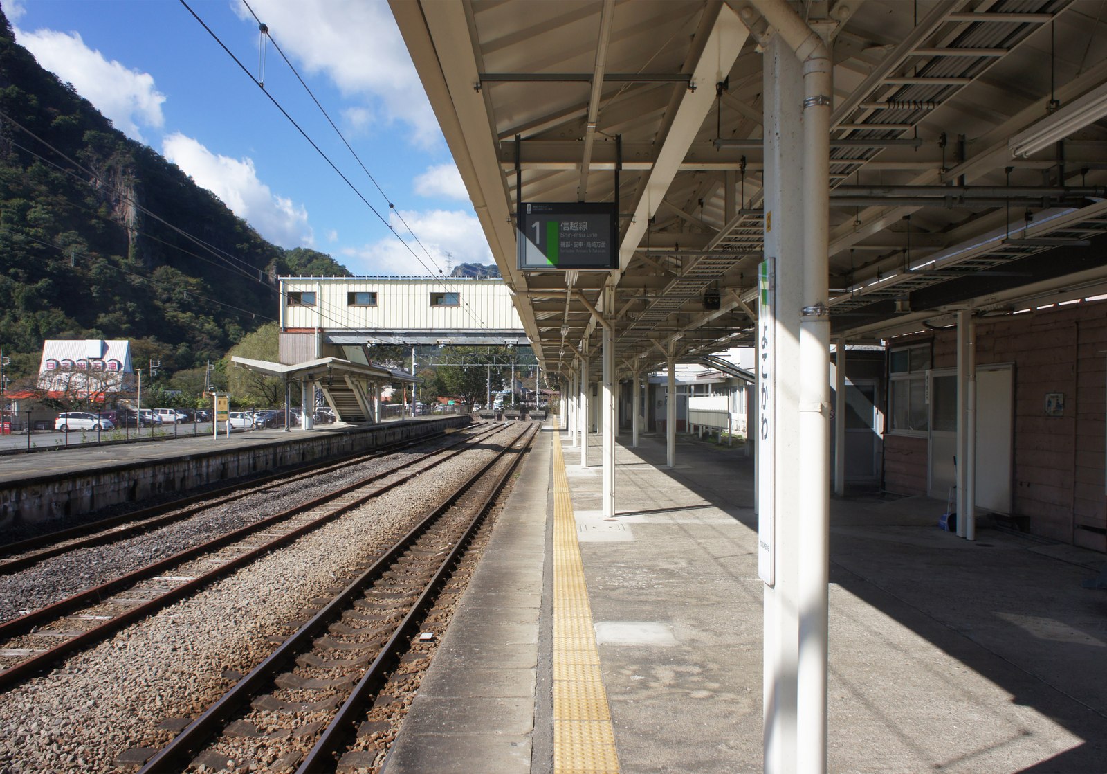 JR信越本線横川駅の1番線ホーム。信越線の案内表示板と、奥に山並みが見える