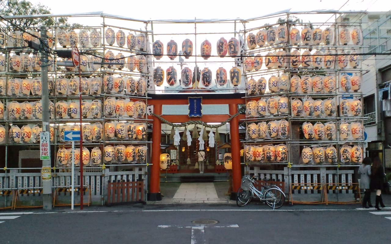 夕方の金刀比羅大鷲神社。朱色の鳥居の両脇に組んだ枠に、奉納の提灯が何段にもぎっしり掛かっている