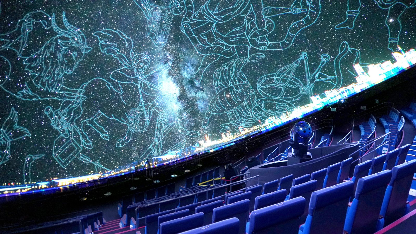 星座線と満天の星を映し出すプラネタリウムドーム内部、階段状の客席